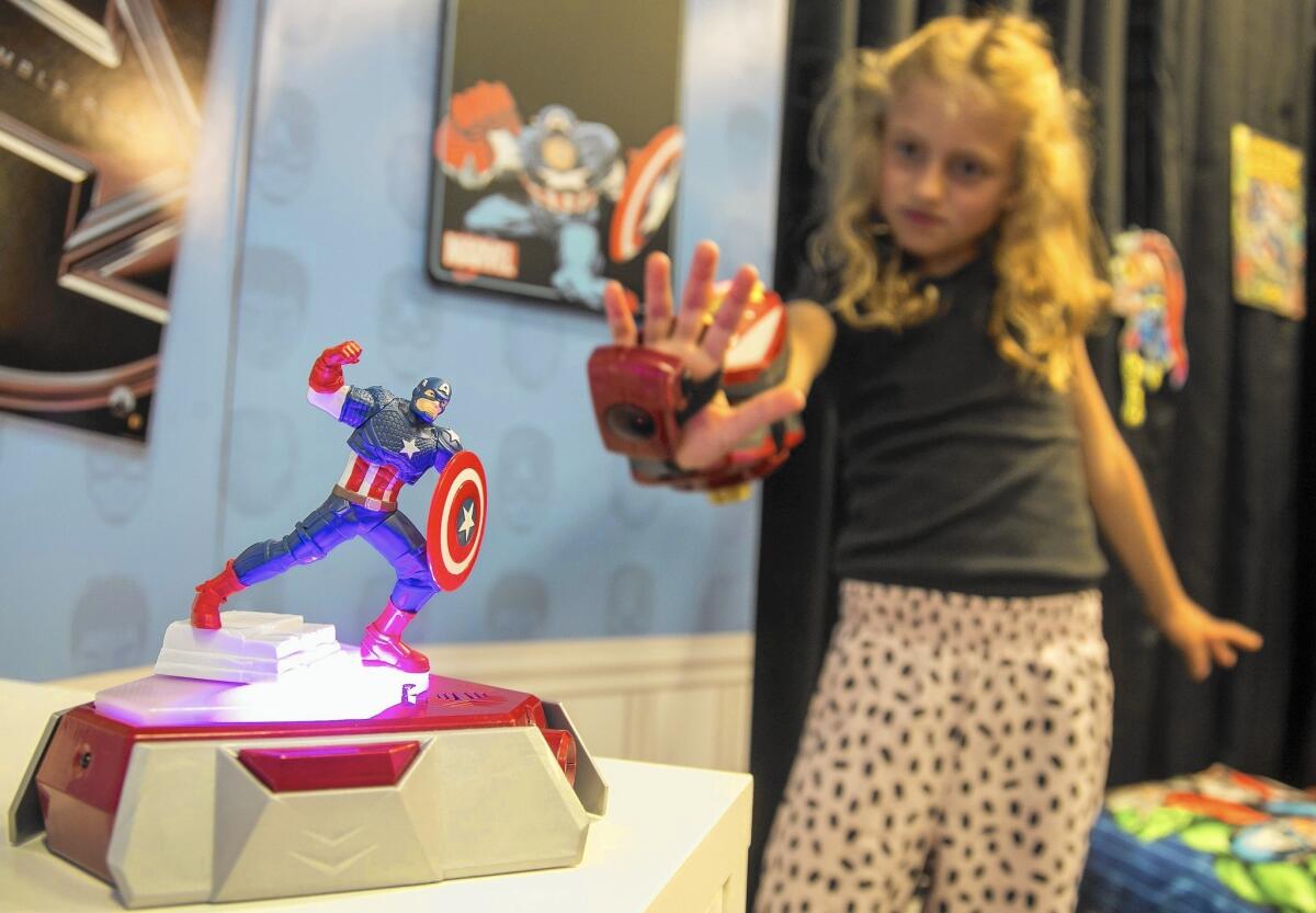 Child wearing Repulsor Gear aiming at a Captain America smart figure on a glowing Power Activator